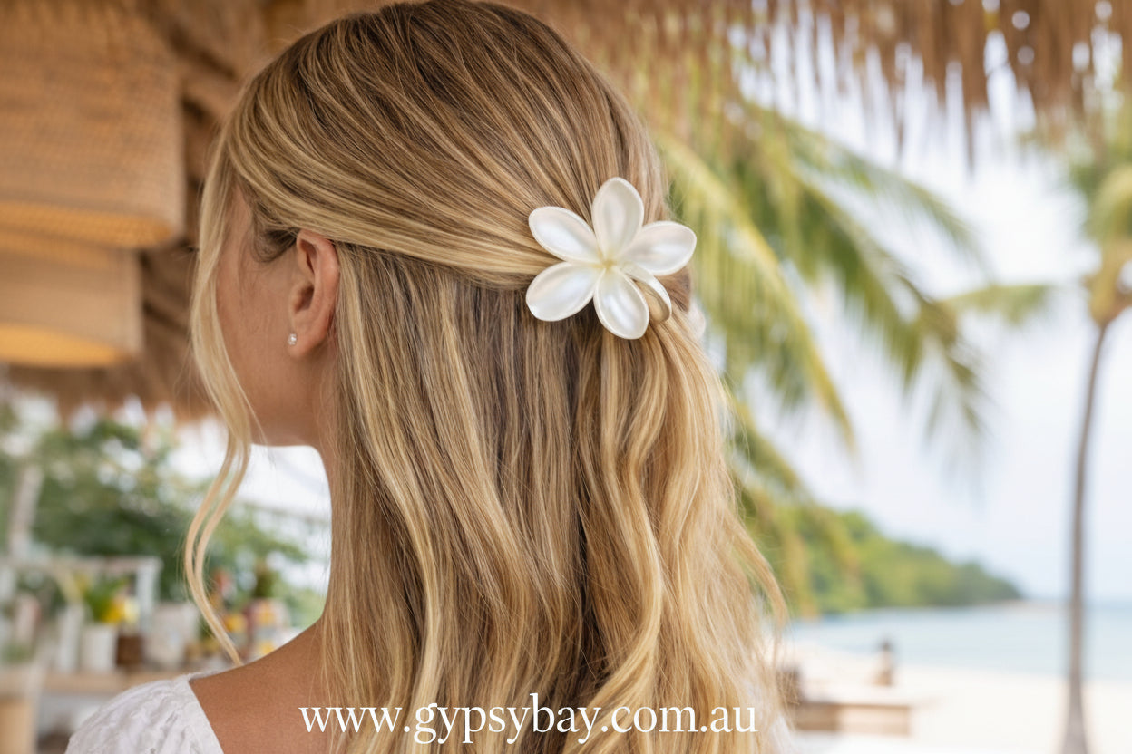 Woman with blonde hair wearing a white flower hair clip outdoors.