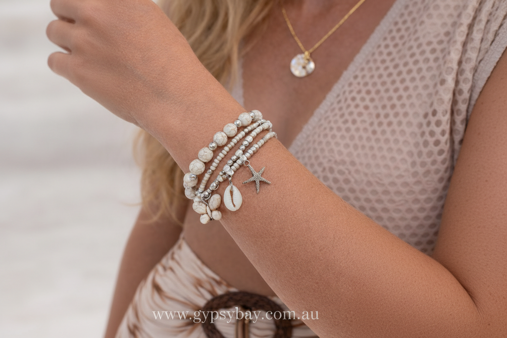 Close-up of a person's arm wearing multiple bead and shell bracelets with a starfish charm.