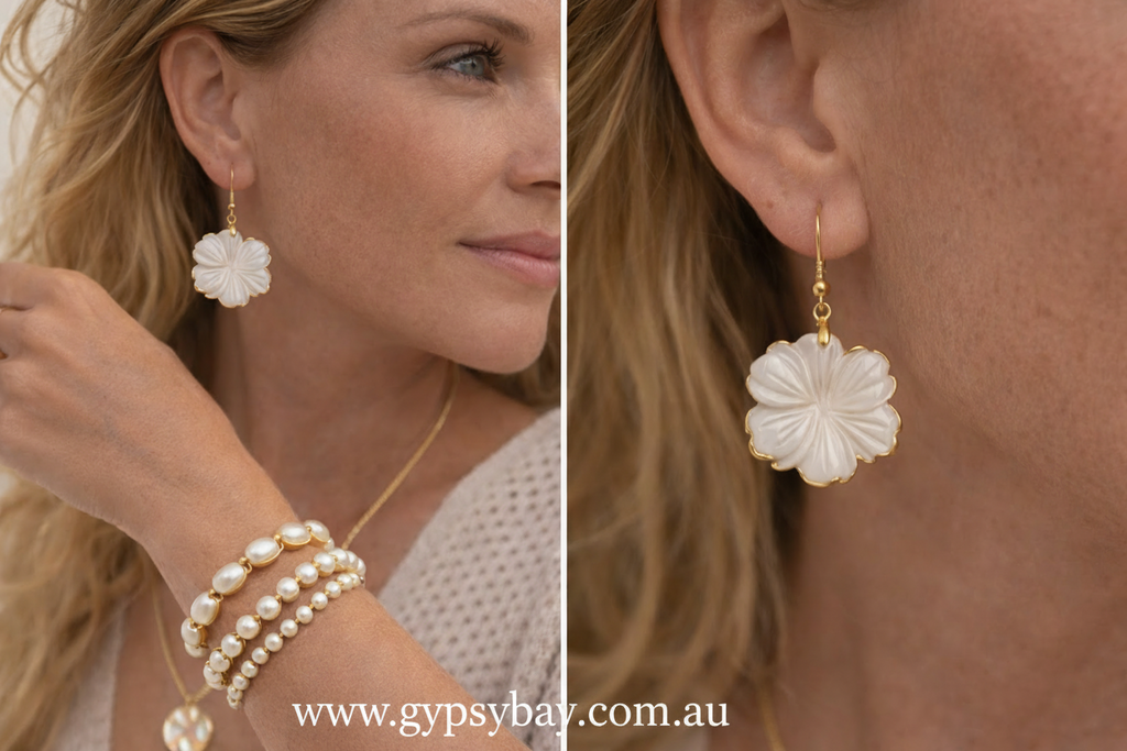 Close-up of a woman wearing gold earrings with floral designs, paired with pearl bracelets.