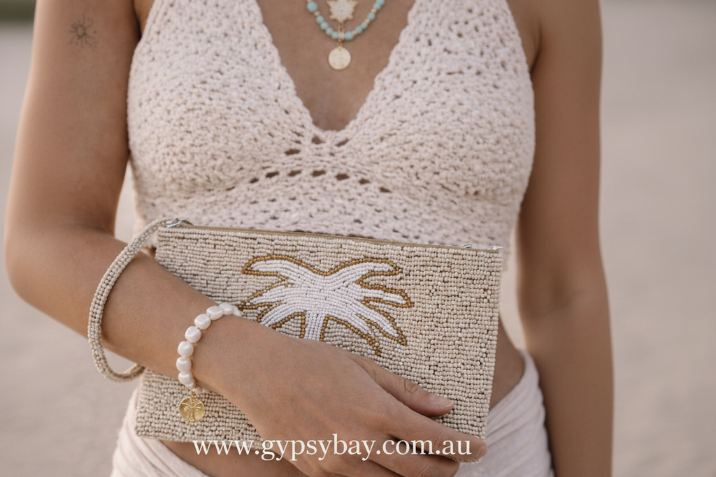 Person holding a beaded clutch with palm tree design, wearing a matching outfit.