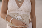 Person holding a beaded clutch with palm tree design, wearing a matching outfit.