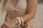Close-up of a person wearing two bracelets on a blurred beach background